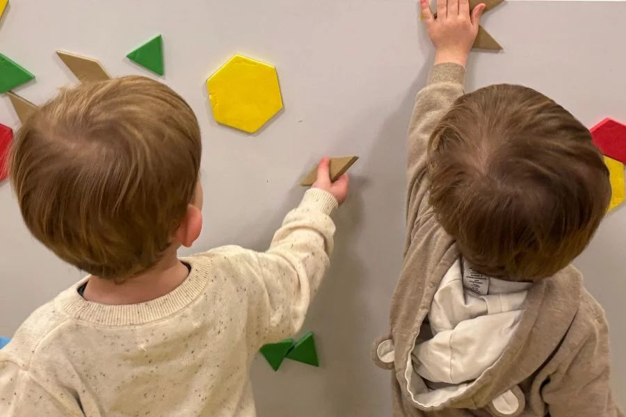 two toddlers playing with a magnet board